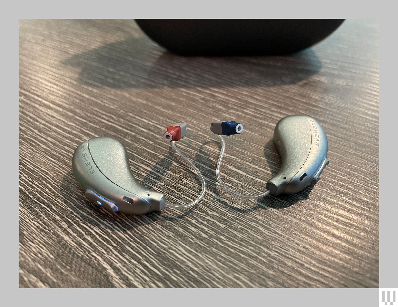 Elehear Beyond a pair of grey behindtheear hearing aids sitting on a brown surface