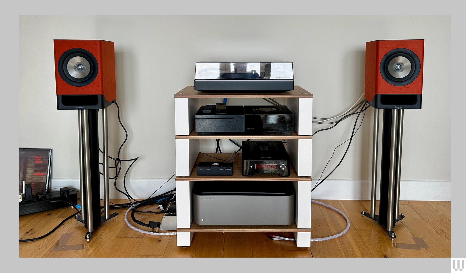 Two of the Technics SC CX700 wireless speakers on stands on either side of a media console