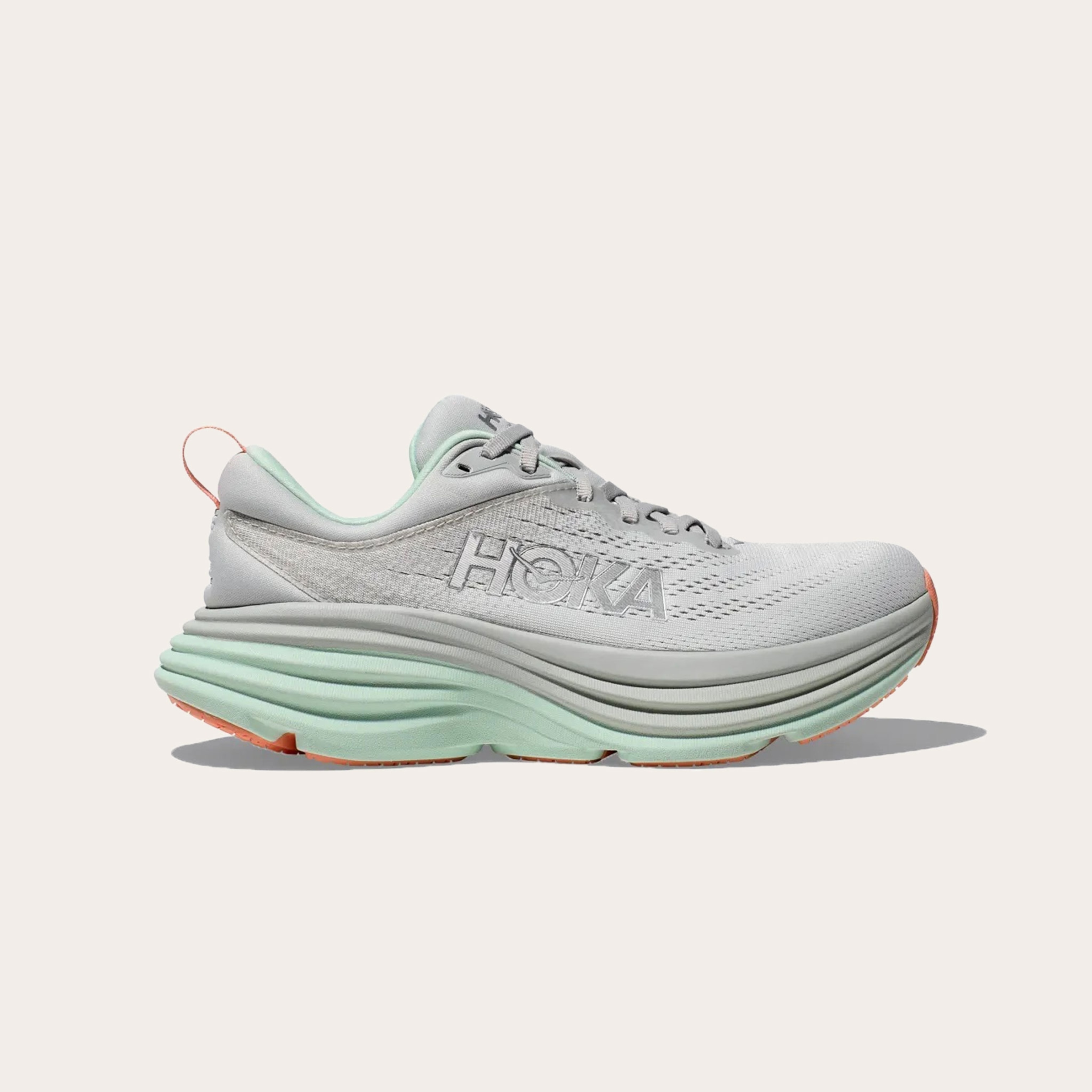 Light grey and teal running shoes placed on tan background.