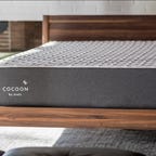 A gray Cocoon by Sealy mattress on a wooden bed frame.